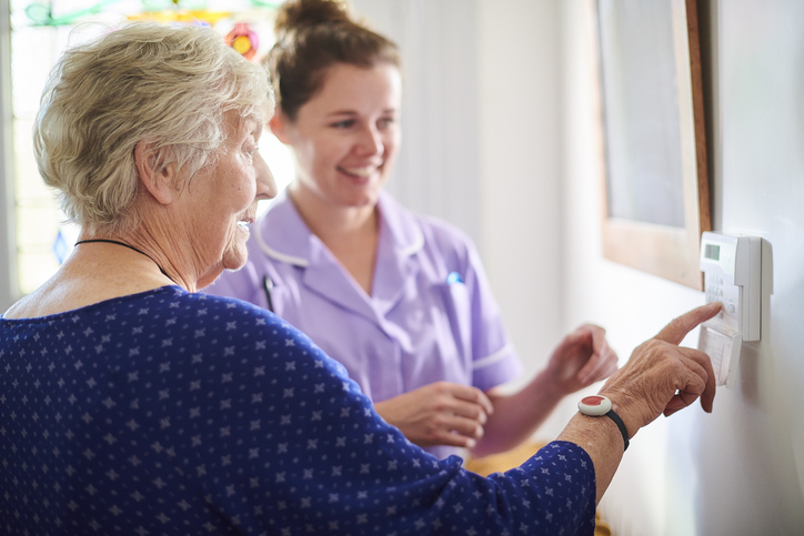 Home carer showing senior woman her alarm panel.