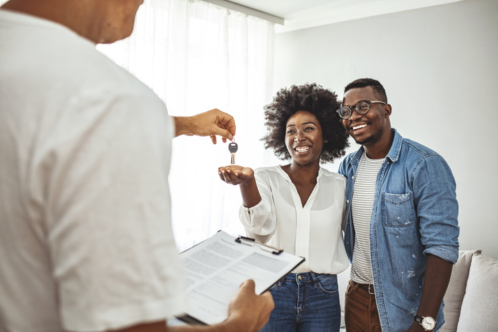 Handsome Real Estate Agent is giving key to the new apartment to happy young couple.