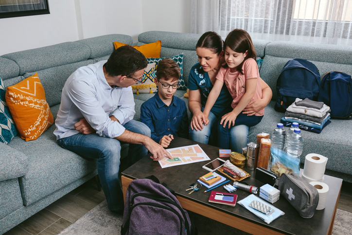 Father explaining to his family the assembly point map while preparing emergency backpacks