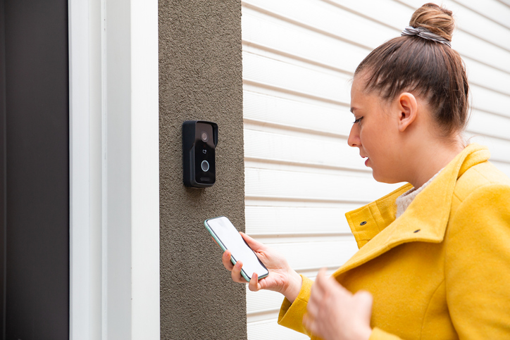 Woman using a camera doorbell to enter a building