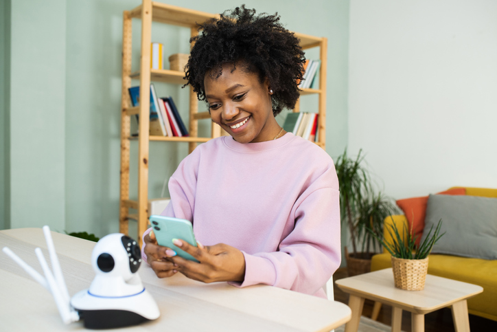 Portrait of a young woman sets up a surveillance camera for her apartment