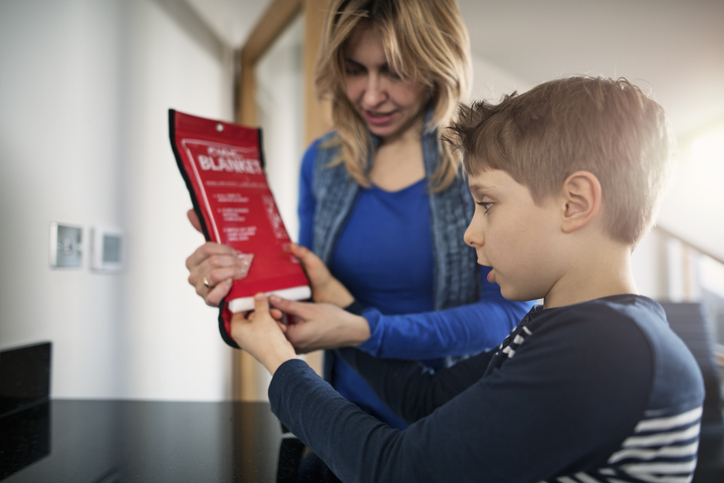 Mother explaining purpose and usage of fire blanket to her son.