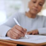 a middle ages African American woman filling out a home checklist in her living room.