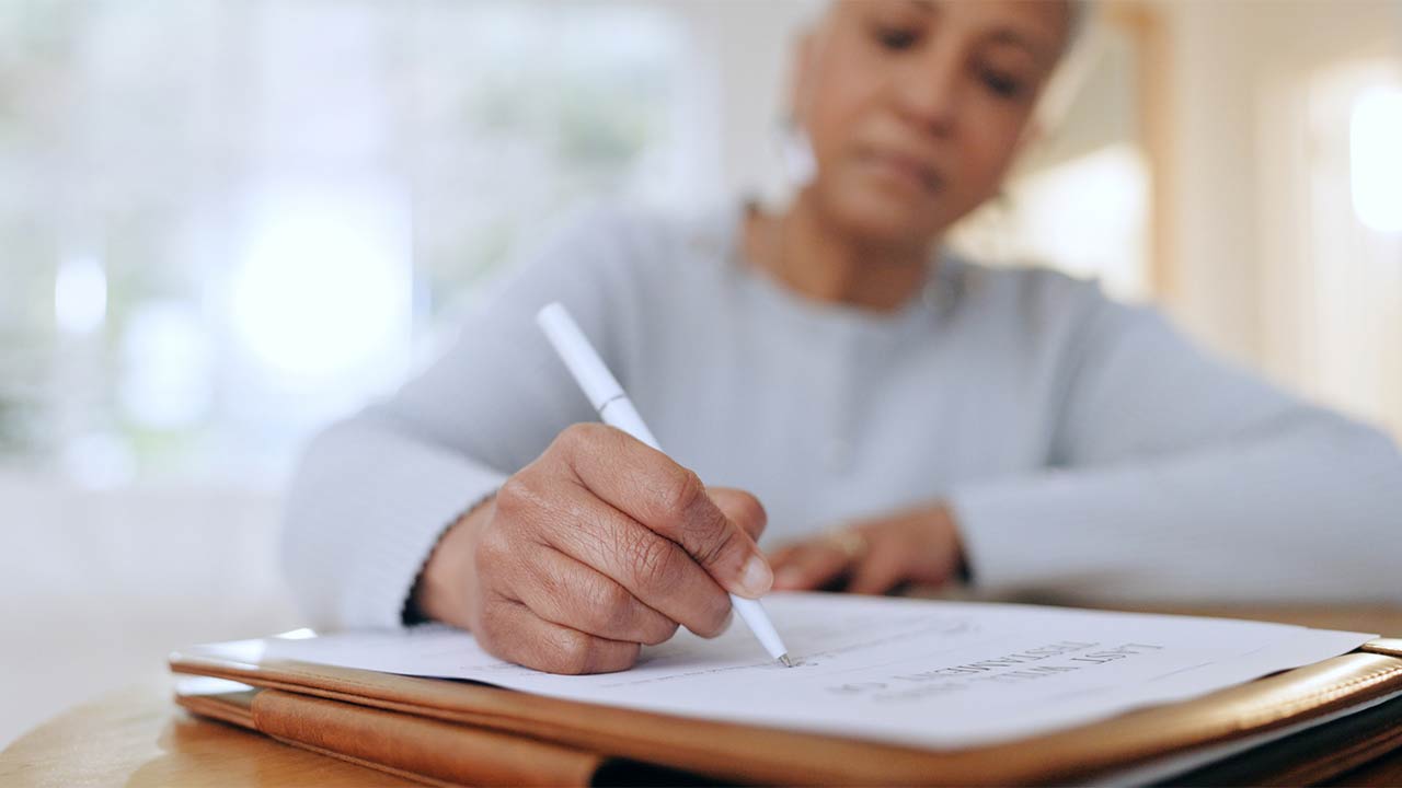 a middle ages African American woman filling out a home checklist in her living room.